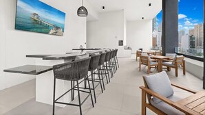 Eine moderne Küche mit Barbereich, einem Essbereich mit Holzmöbeln und einem großen Fenster mit Blick auf die Stadt.