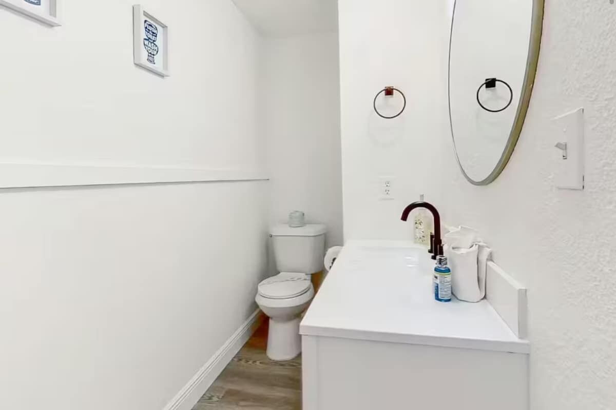 A small, white bathroom with a toilet, sink, and mirror.