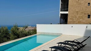 A swimming pool with lounge chairs, a clear view of the sea, and a building with a beige facade. - Valentina - Corfu View Residence (Sarandë)