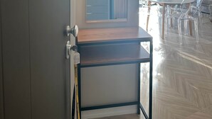 Un interno moderno con una porta in legno, uno specchio, un tavolino e un'area pranzo con sedie trasparenti.