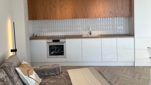 Una cucina moderna con mobili bianchi, pensili in legno e un forno integrato.