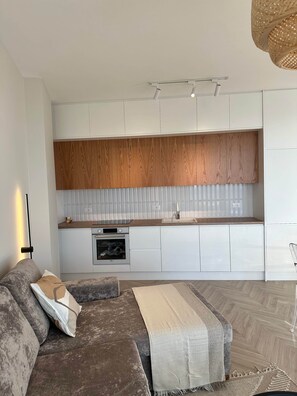 A modern kitchen with white cabinets, wooden upper cabinets, and a built-in oven. - Veronica - Corfu View Residence (Sarandë)