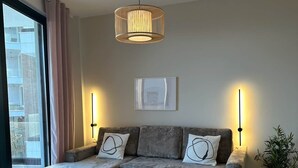 Un salon moderne avec un canapé d’angle gris, une table basse en verre et une suspension.