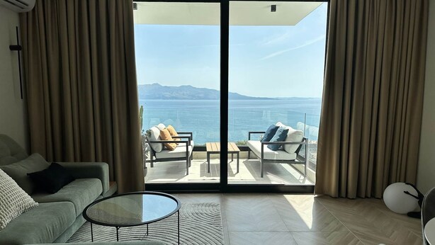 Un salon moderne avec un canapé, une table basse et un balcon offrant une vue sur la mer.