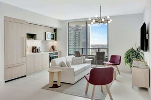 Eine moderne Wohnung mit Wohnbereich, Küche und Balkon mit Blick auf die Stadt.