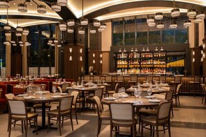 Ein Restaurant mit runden Tischen, Stühlen und einer Bar mit Regalen voller Flaschen.
