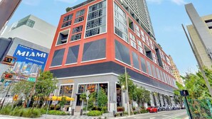 A modern building with a prominent red and grey facade, large windows, and a visible entrance.