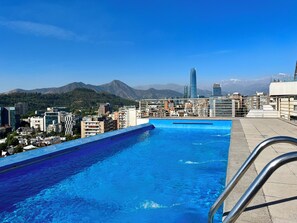 Ein Pool auf dem Dach mit Blick auf die Stadtlandschaft, einschließlich Bergen und modernen Gebäuden.