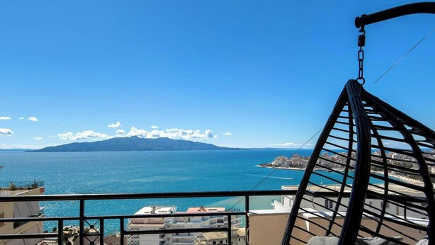 Un balcon avec vue sur la mer et les montagnes au loin.