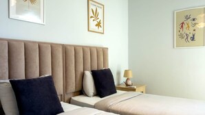 Une chambre d’hôtel avec deux lits, une tête de lit, une table de chevet et des œuvres d’art murales.