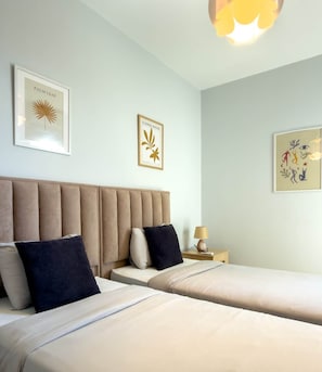 Ein Hotelzimmer mit zwei Betten, einem Kopfteil, einem Nachttisch und Wandbildern.