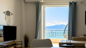 Un salon moderne avec une table ronde, un téléviseur à écran plat, une décoration murale et une vue sur la mer.