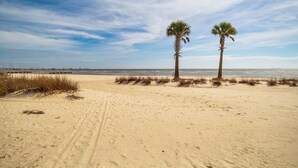 Une plage de sable avec deux palmiers et un ciel dégagé.