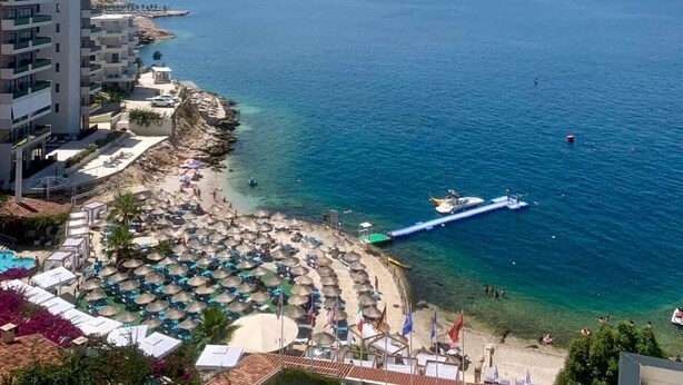 Un complejo turístico frente al mar, con playa, piscina y vistas al océano.