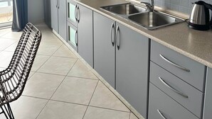 Una cocina moderna con gabinetes grises, un lavamanos de acero inoxidable y un hervidor.