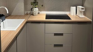 Een moderne keuken met een witte spoelbak, een houten aanrechtblad en grijze kastjes.