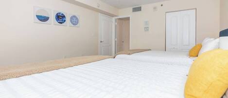 A bedroom with two beds, a ceiling fan, and wall art.