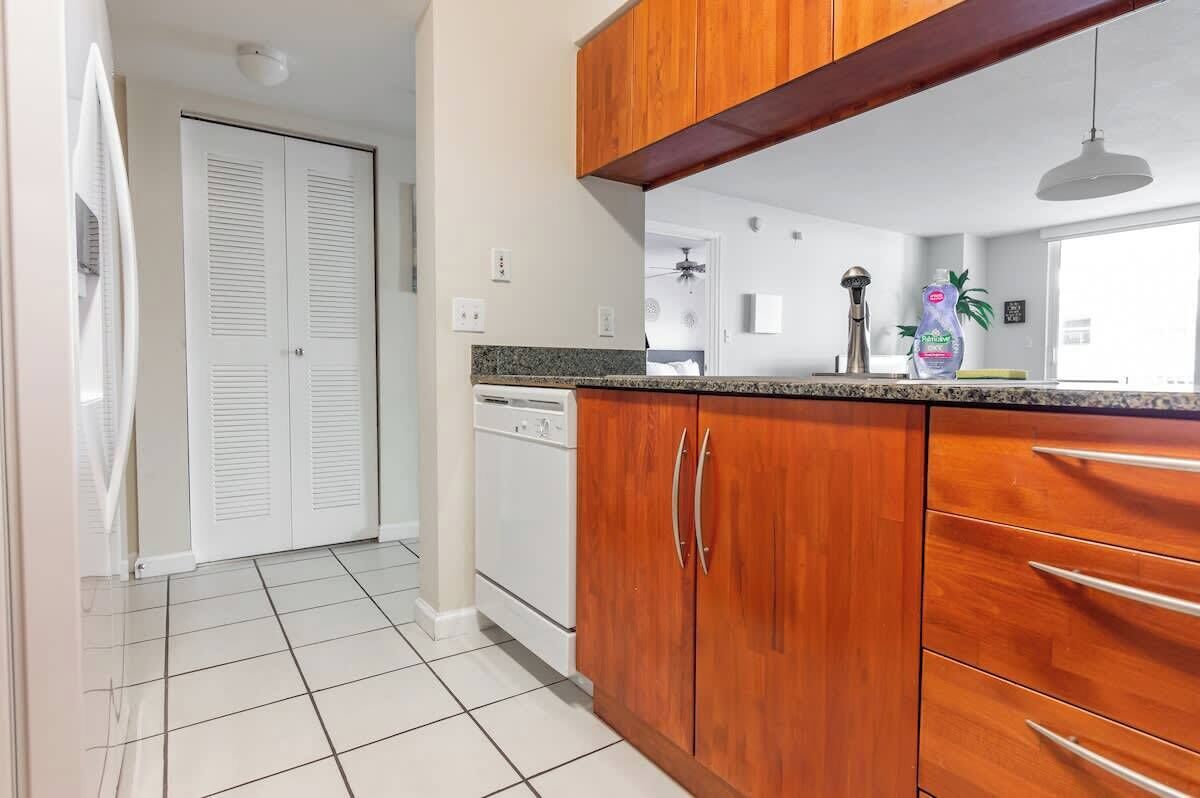 A kitchen with wooden cabinets, a granite countertop, and a white refrigerator.