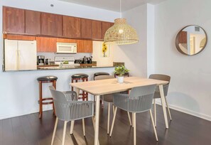 A modern kitchen with wooden cabinets, a microwave, and a hanging pendant light. - Prime Brickell Stay with Pool, Gym & Parking (Miami)