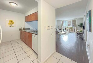 Eine moderne Küche mit Holzausstattung, einem Geschirrspüler und einem Essbereich mit einem Glastisch und Stühlen.