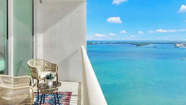 Een balkon met rieten meubilair en uitzicht op zee.