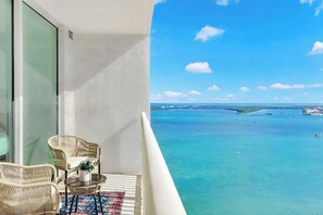 Un balcon doté de meubles en osier et offrant une vue sur la mer.