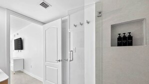 Een moderne badkamer met een douchecabine van glas, een wit toilet en een wastafel met spiegel.