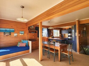 L’intérieur chaleureux d’un chalet avec un coin repas en bois, un canapé bleu et une cuisine équipée d’appareils modernes.