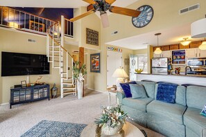 A spacious living area with a staircase, a television, a sofa, and a kitchen area. - 180 Main Channel View! Poolside Apt in Osage Beach (Osage Beach)