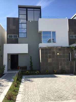A modern building with a flat roof, large windows, and a paved driveway.