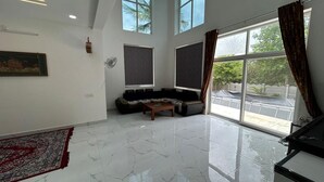 Un salón amplio con techo alto, ventanas grandes, un sofá y una mesa de centro.