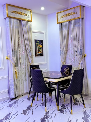 A dining area with a round table, four chairs, and a framed artwork on the wall.