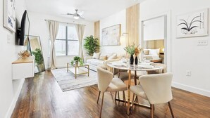 A modern living room with a dining area, wooden flooring, and a ceiling fan. - Zen 2B2B Next to Legacy West (Frisco)