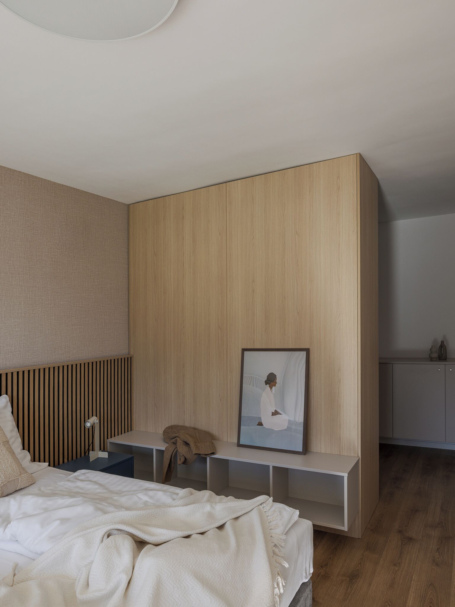 Une chambre à coucher comprenant un lit, une table de chevet, une étagère et un tableau encadré accroché au mur.