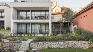 Un moderno edificio de dos plantas con balcones, un muro de piedra de contención y un jardín bien cuidado.