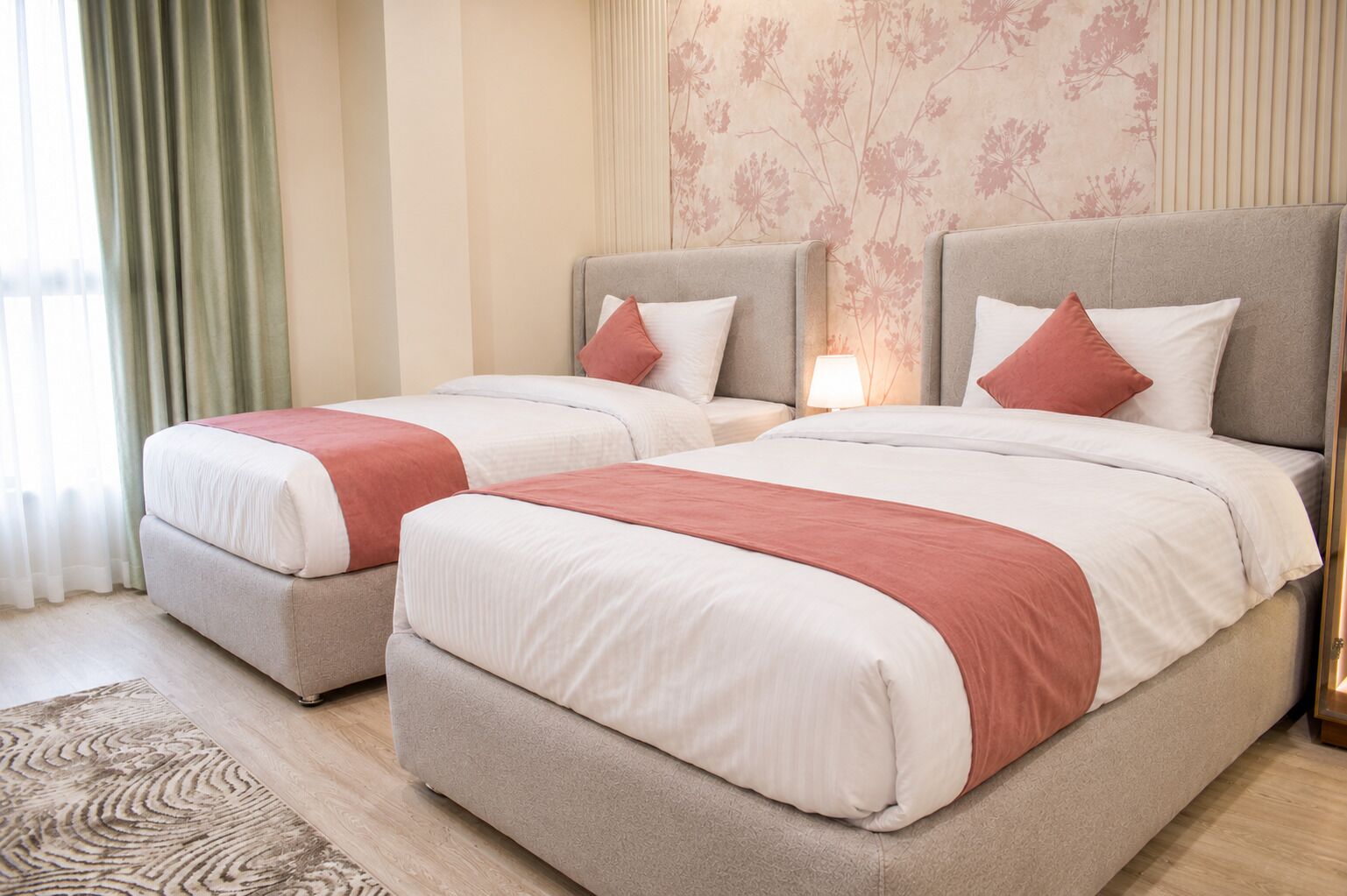 Una habitación de hotel con dos camas, un tapete estampado y papel tapiz floral.