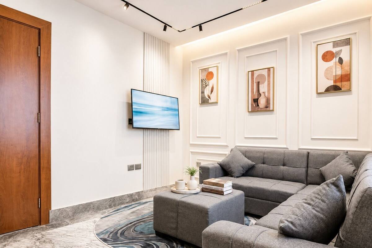 A modern living room with a grey sectional sofa, a flat-screen TV, and abstract wall art.