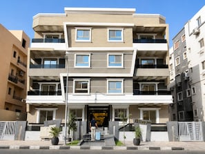 A multi-story hotel with a modern design, featuring balconies, a central entrance, and a sign indicating it's a Stay Inn. - Stay inn 51 (Sheikh Zayed City)