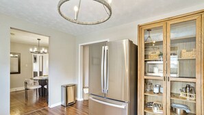 A modern kitchen with a stainless steel refrigerator, wooden cabinets, and a dining area with a round table and chairs. - Holbrook ~ Cozy Guest Retreat (Knoxville)