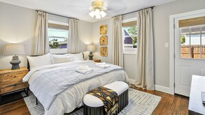 A bedroom with a large bed, bedside lamps, a ceiling fan, and a view of the outdoors. - Holbrook ~ Cozy Guest Retreat (Knoxville)