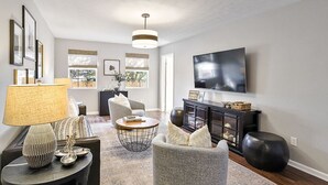 A modern living room with a sofa, coffee table, and a TV mounted on the wall. - Holbrook ~ Cozy Guest Retreat (Knoxville)