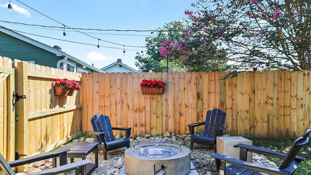 A backyard with a hot tub, two Adirondack chairs, a wooden fence, and flower baskets. - Holbrook ~ Cozy Guest Retreat (Knoxville)
