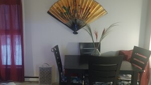 A room with a dining table, chairs, a fan, and a window with red curtains. - Spacious renovated 2 1/2 sleeps 3 (Montréal)