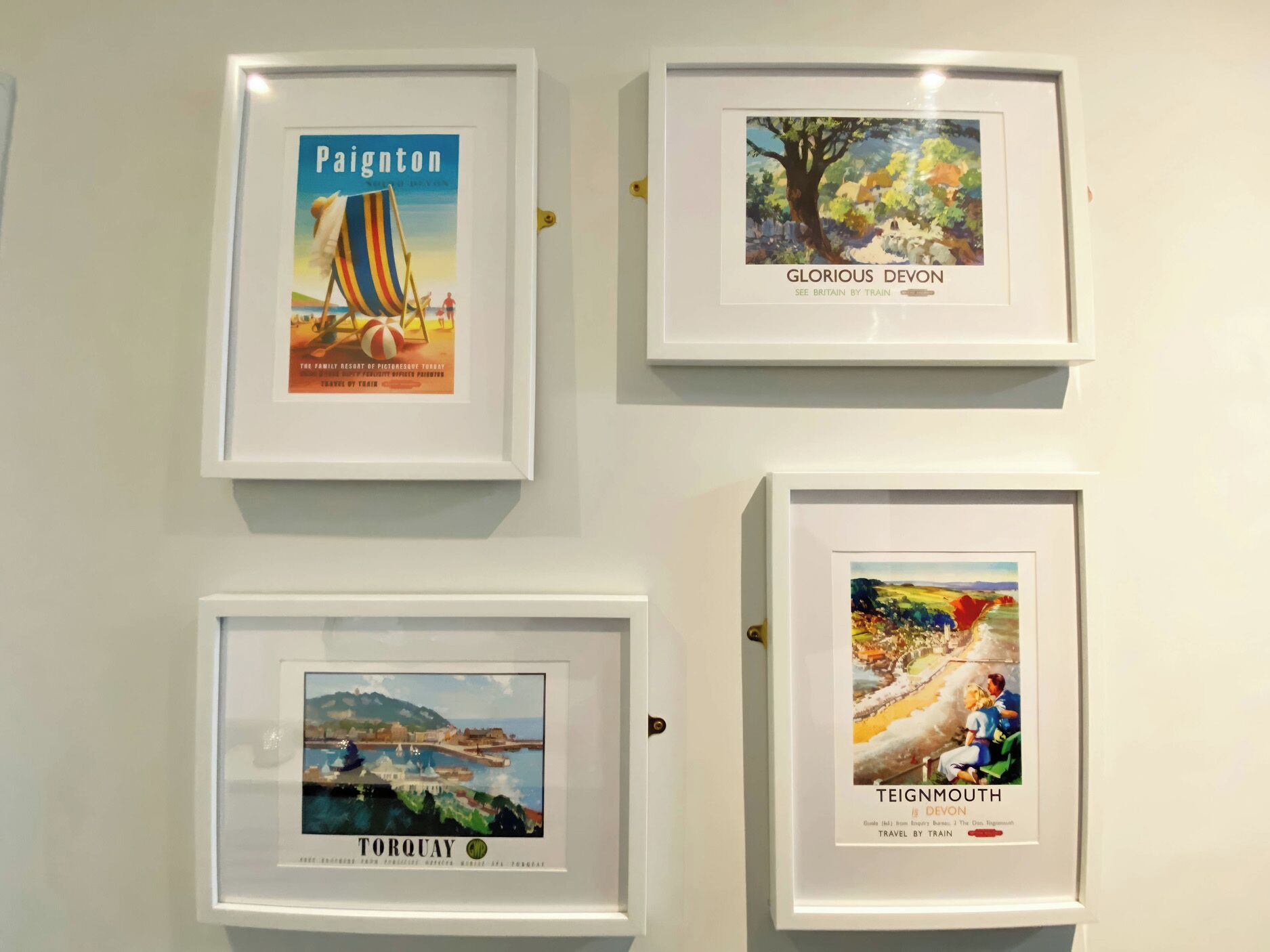 Four framed travel posters on a wall.