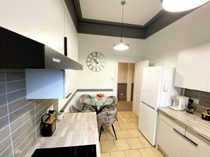 Una cocina moderna con estufa integrada, cafetera y comedor con mesa y sillas.