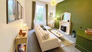 A cozy living room with a white sofa, a fireplace, and a green accent wall. - 2B Redcliffe (Torquay)