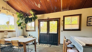 A room with a wooden ceiling, a black door, a dining table with chairs, and a bar area. - Country Carriage House in Downtown Geyserville, Vineyard Views (Geyserville)