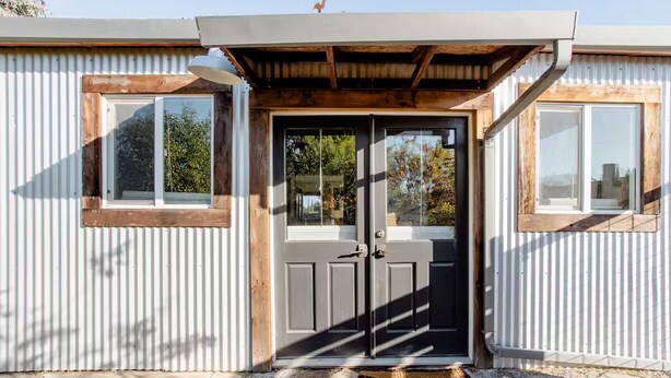 A modern building with a metal exterior, a wooden door, and a small window on the side. - Country Carriage House in Downtown Geyserville, Vineyard Views (Geyserville)