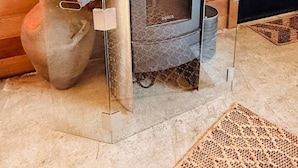 A compact wood-burning stove with a glass door, positioned against a wooden wall with a mirror above it. - Country Carriage House in Downtown Geyserville, Vineyard Views (Geyserville)