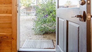A wooden door leading to a covered outdoor area with a bench and an umbrella. - Country Carriage House in Downtown Geyserville, Vineyard Views (Geyserville)